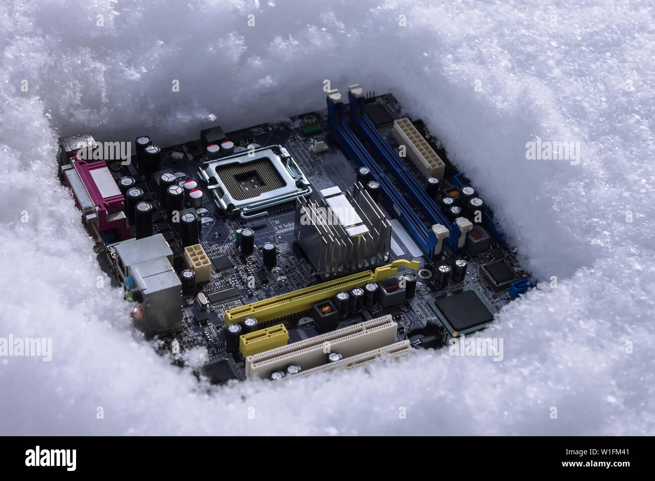A computer motherboard with a processor lying on a dump in the snow ...