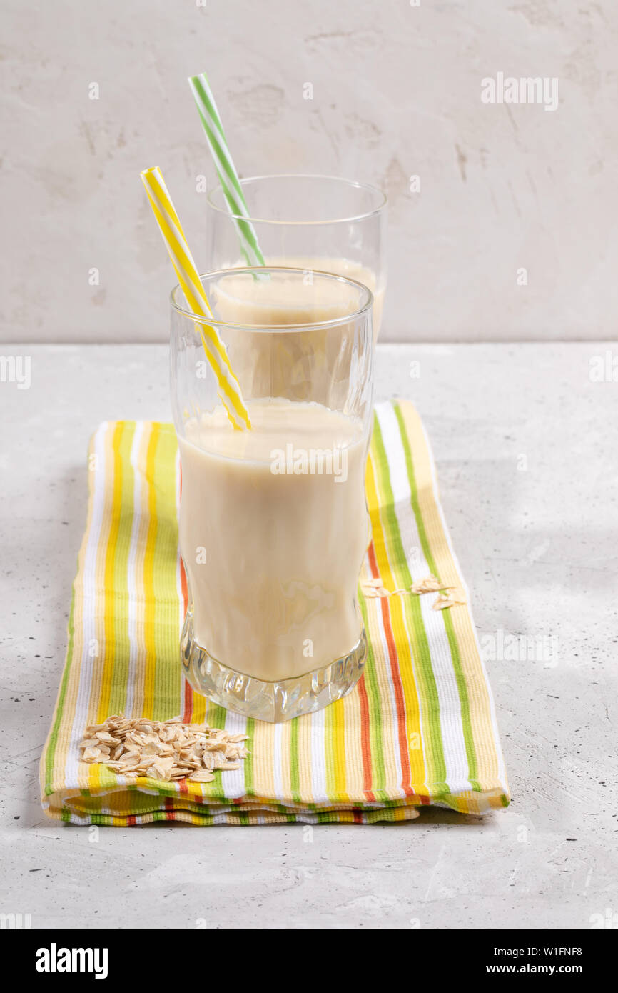 Two glasses with oat milk with drinking straws on yellow-green kitchen towel.  Stock Photo