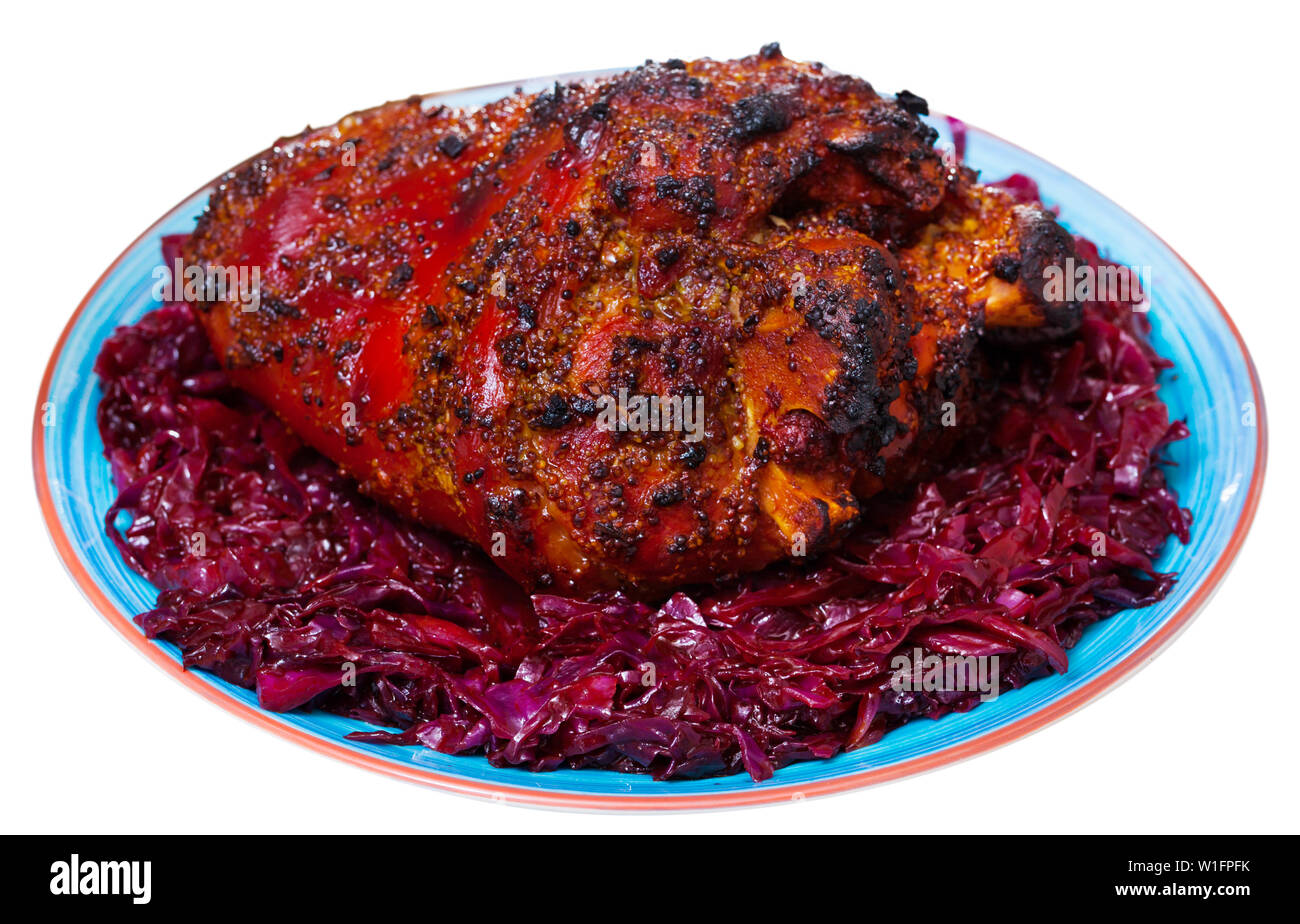 Delicious oven baked pork knuckle with side dish of braised red cabbage and onion. Isolated over