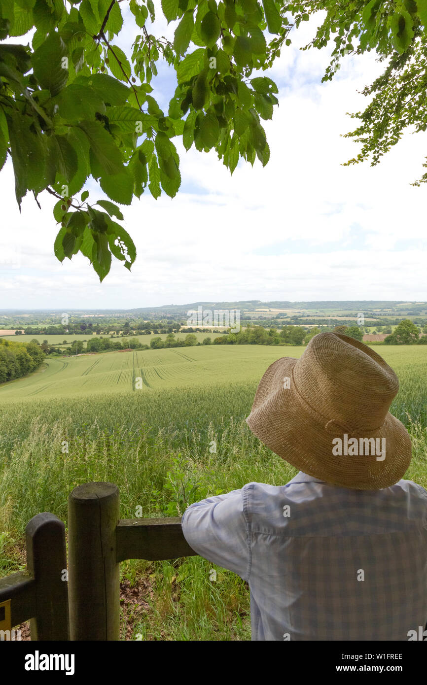English countryside - a woman wearing a straw hat looking out over
