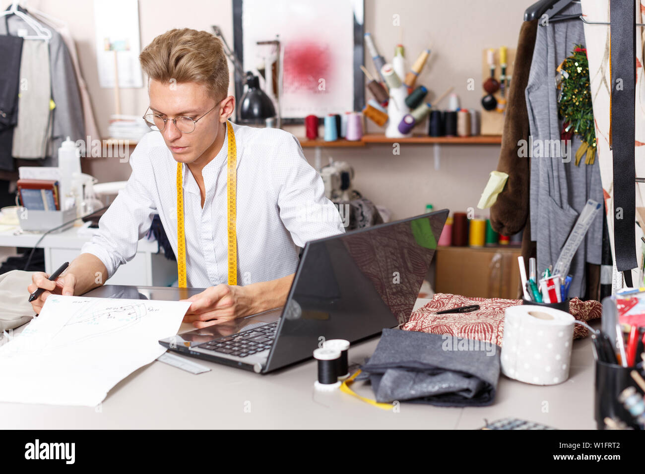 Young male tailor creating  pattern using graphics tablet at sewing atelier Stock Photo