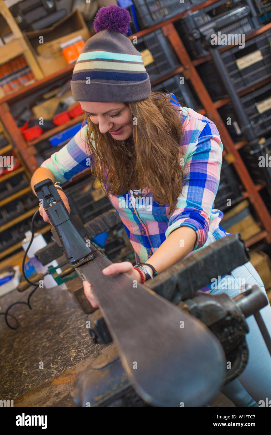 Pretty girl in checkered shirt repairing ski in the workshop Stock Photo