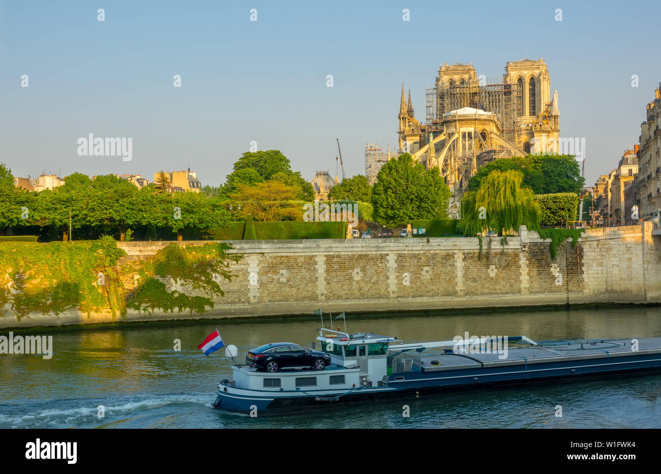 France. Paris. Sunny summer morning on the Seine embankment. Notre Dame in scaffolding after a fire in 2019. Barge on the river Stock Photo