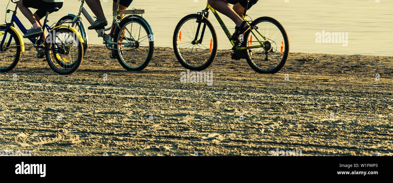 positive family rides bicycles on beach Stock Photo