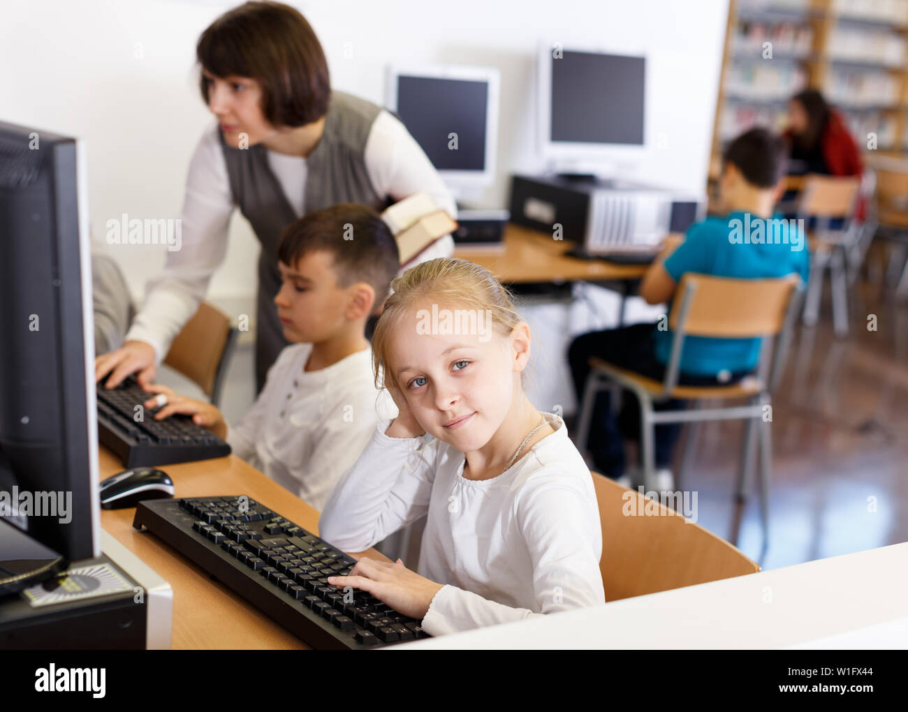 Upset schoolgirl sitting in computer class of school library on ...
