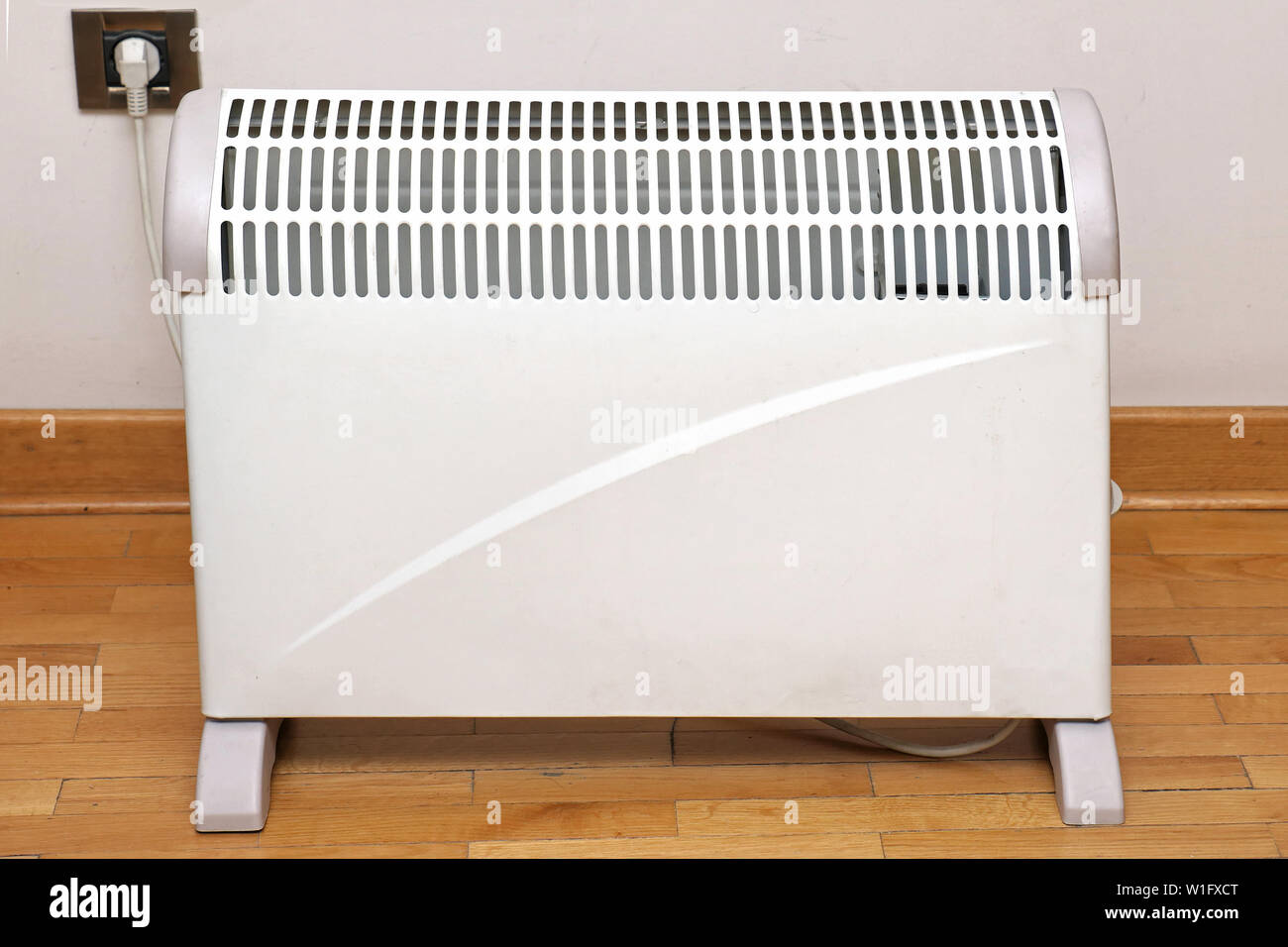 Electric Heater On Wooden Floor Inside Interior And Plugged Into