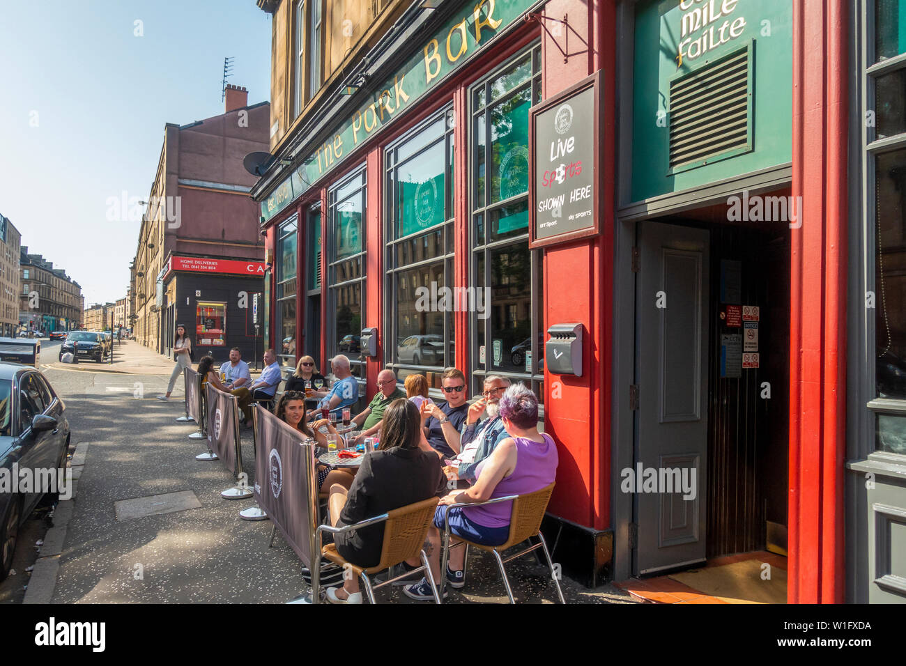 Groups of patrons relaxing and drinking on a hot June afternoon outside the Park Bar in the West End of Glasgow, Scotland Stock Photo