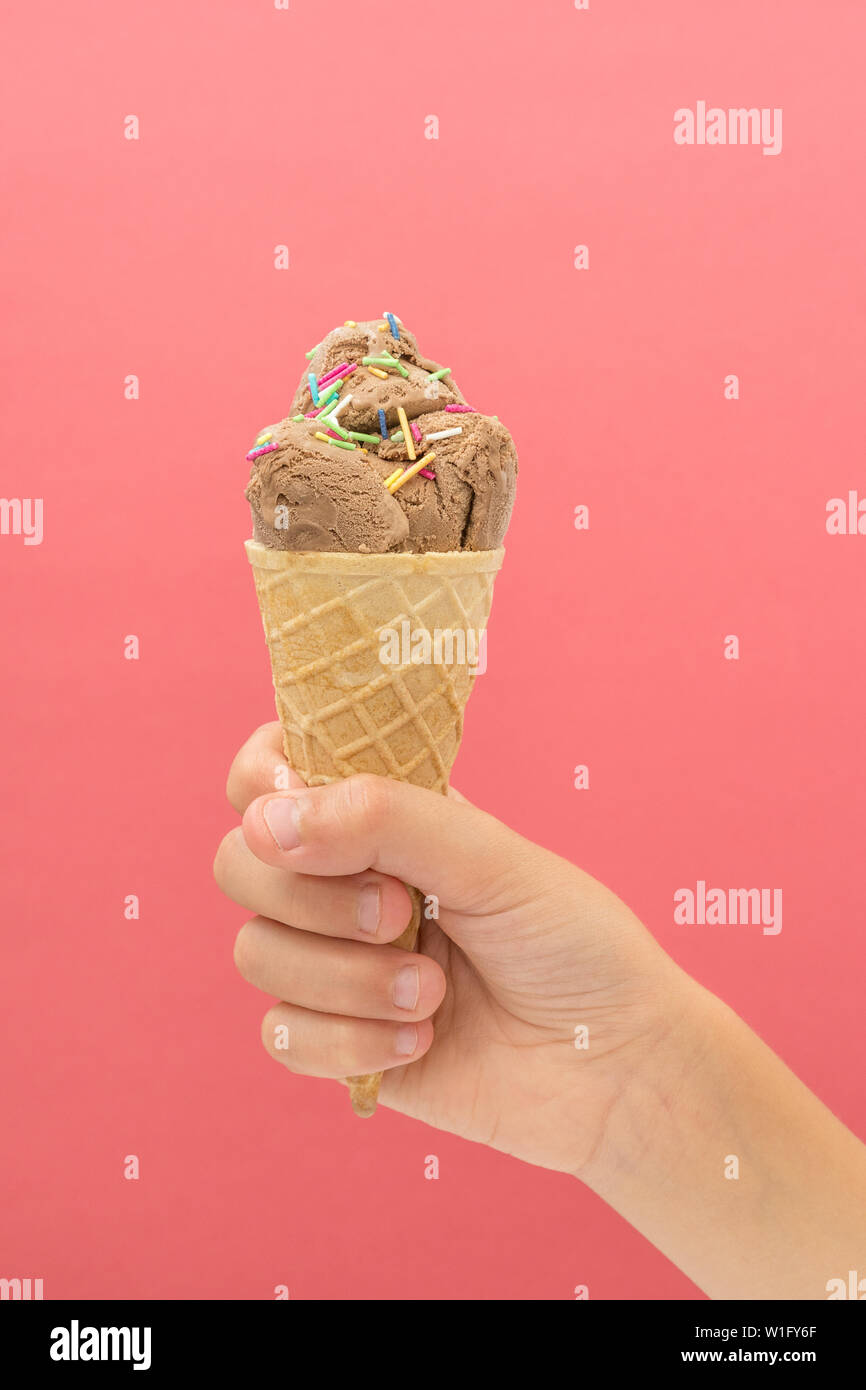 Ice cream cone in hand on pink bright background. Summer desserts Stock