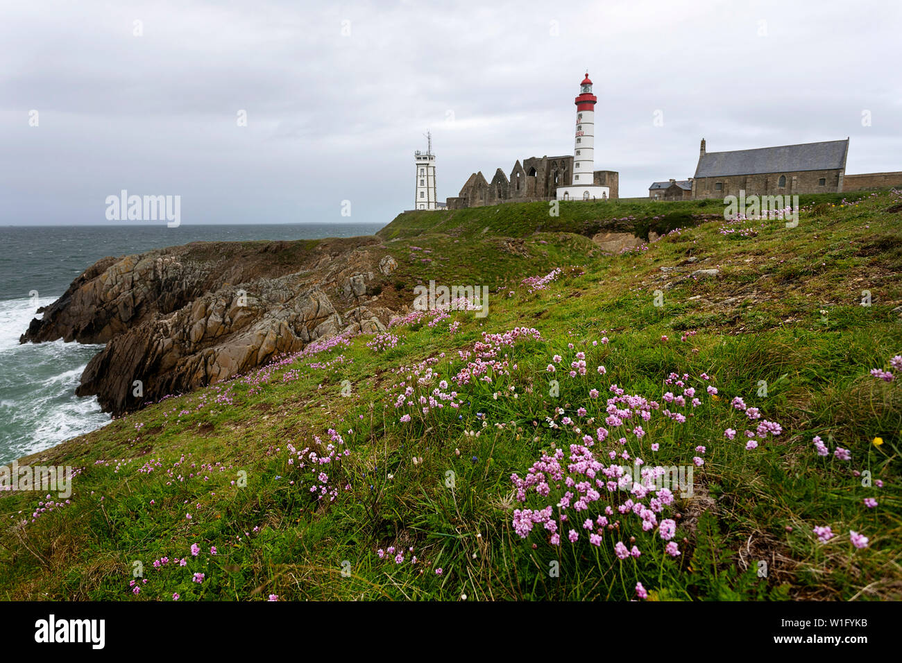 The lighthouse and abbey rise above the sea and rocky coastline at Pointe Saint-Mathieu in Brittany, France Stock Photo