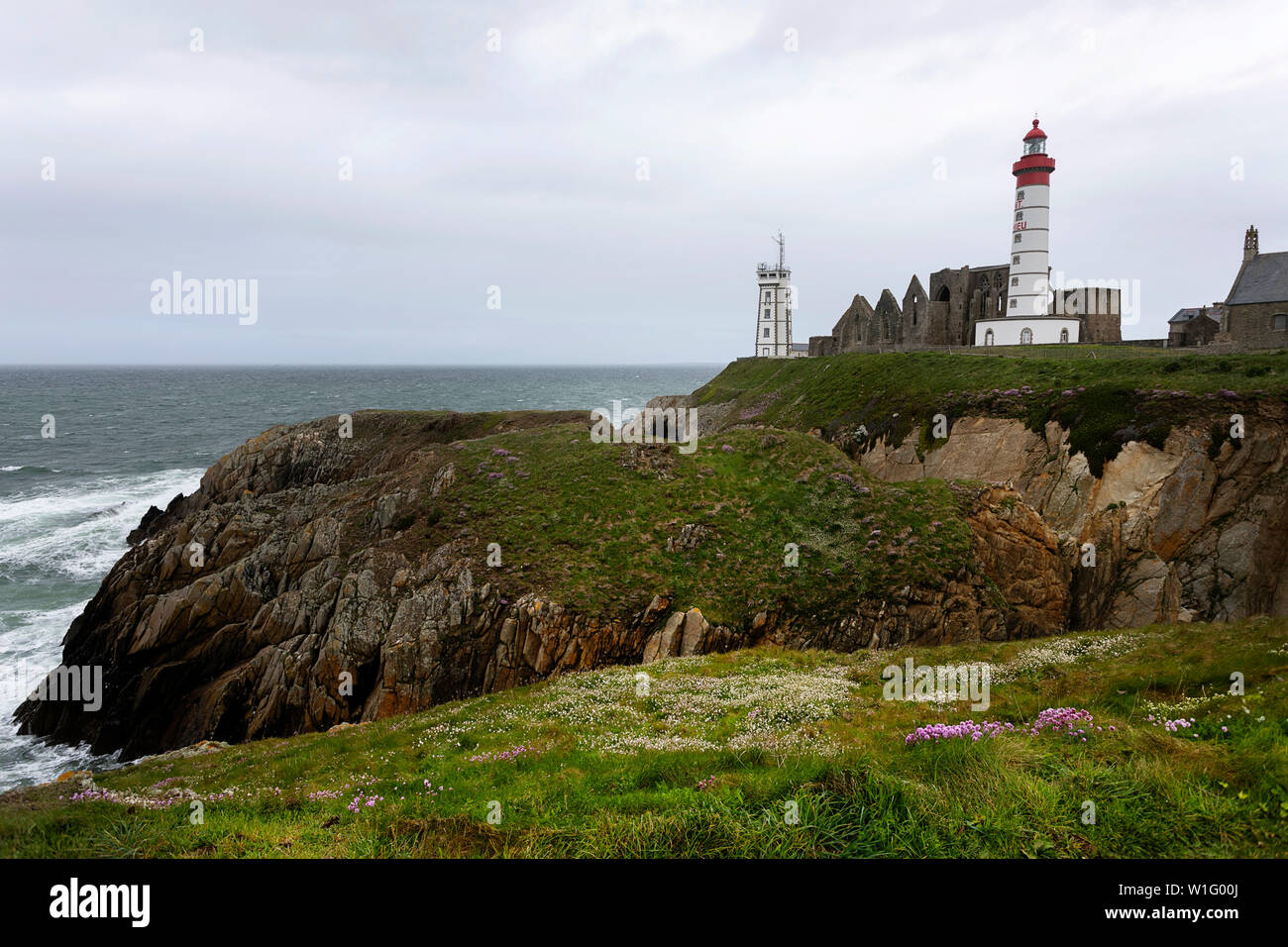 The lighthouse and abbey rise above the sea and rocky coastline at Pointe Saint-Mathieu in Brittany, France Stock Photo