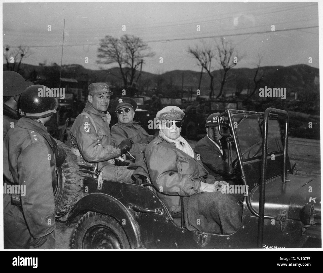 Lieutenant General Matthew Ridgway; Major General Doyle Hickey; and General Douglas MacArthur, Commander in Chief of United Nations Forces in Korea, in a jeep at a command post, Yang Yang, Korea, approximately 15 miles north of the 38th parallel, April 3, 1951.; General notes:  Use War and Conflict Number 1376 when ordering a reproduction or requesting information about this image. Stock Photo