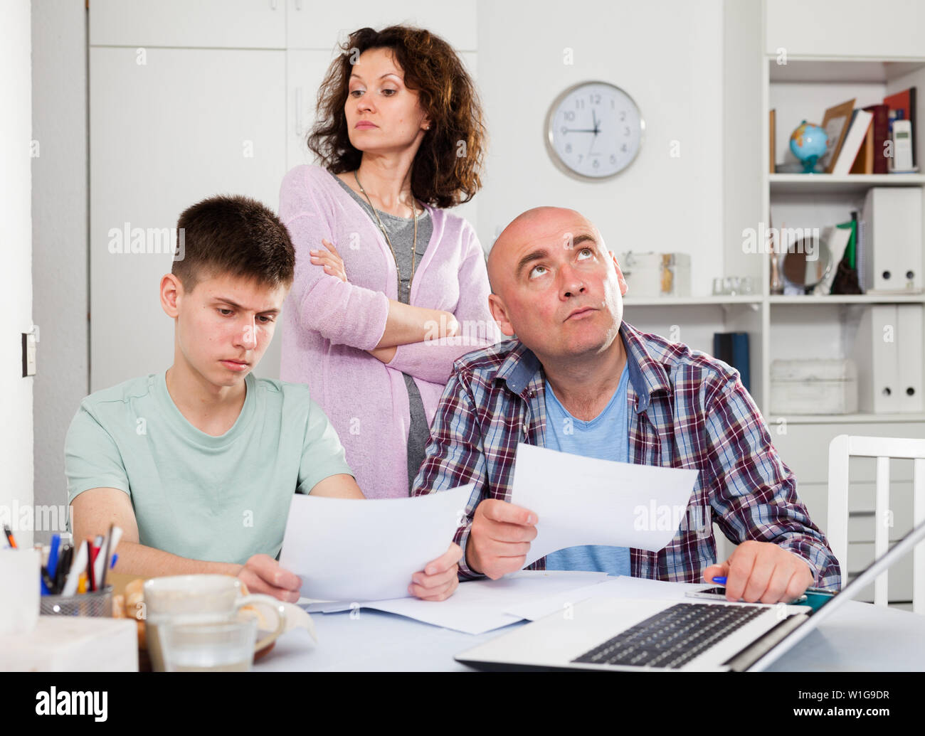 Chagrined family with teenage son working with papers at home Stock ...