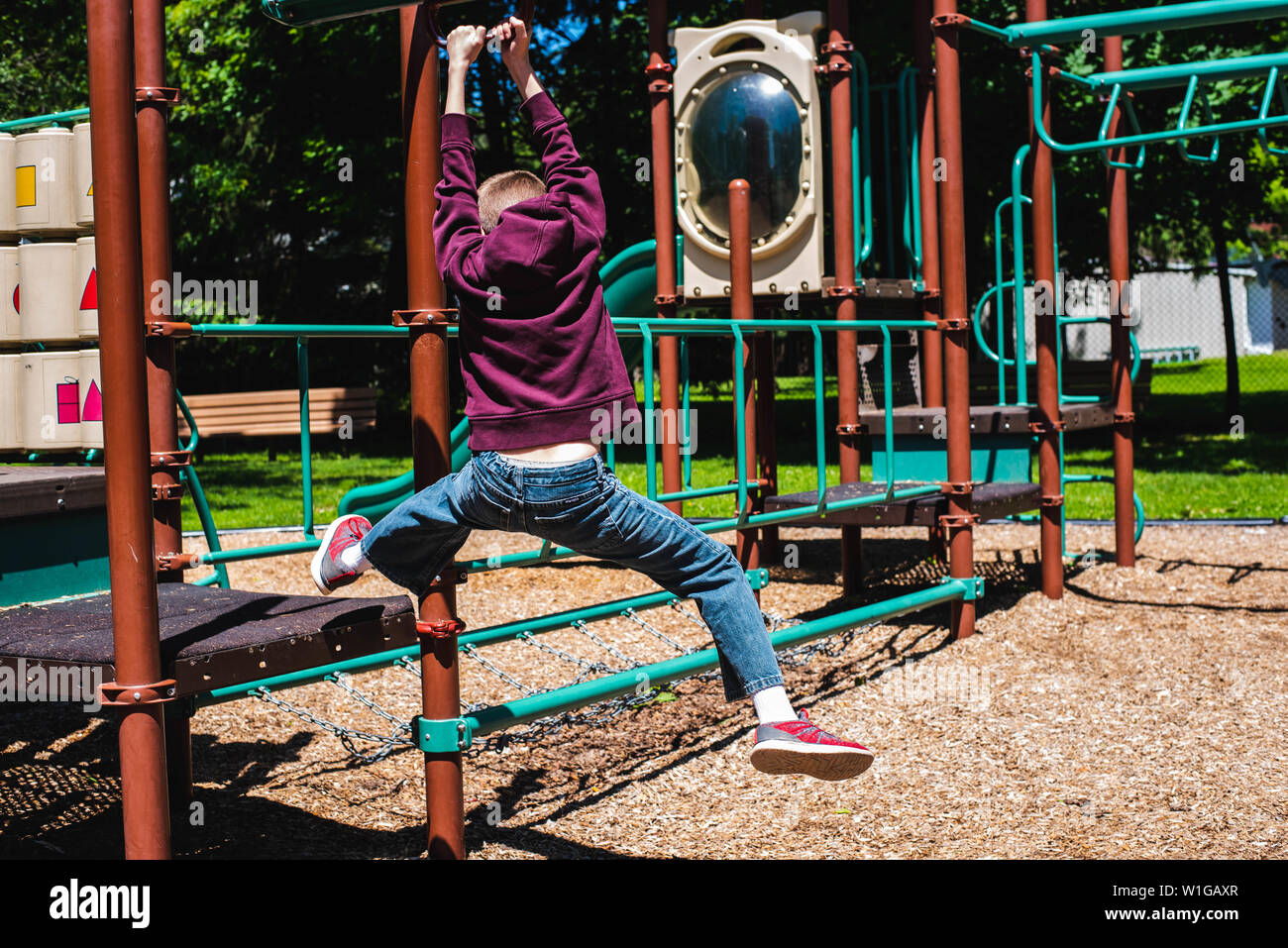 A boy slides on a zip line on a playground on a warm summer day. Stock Photo