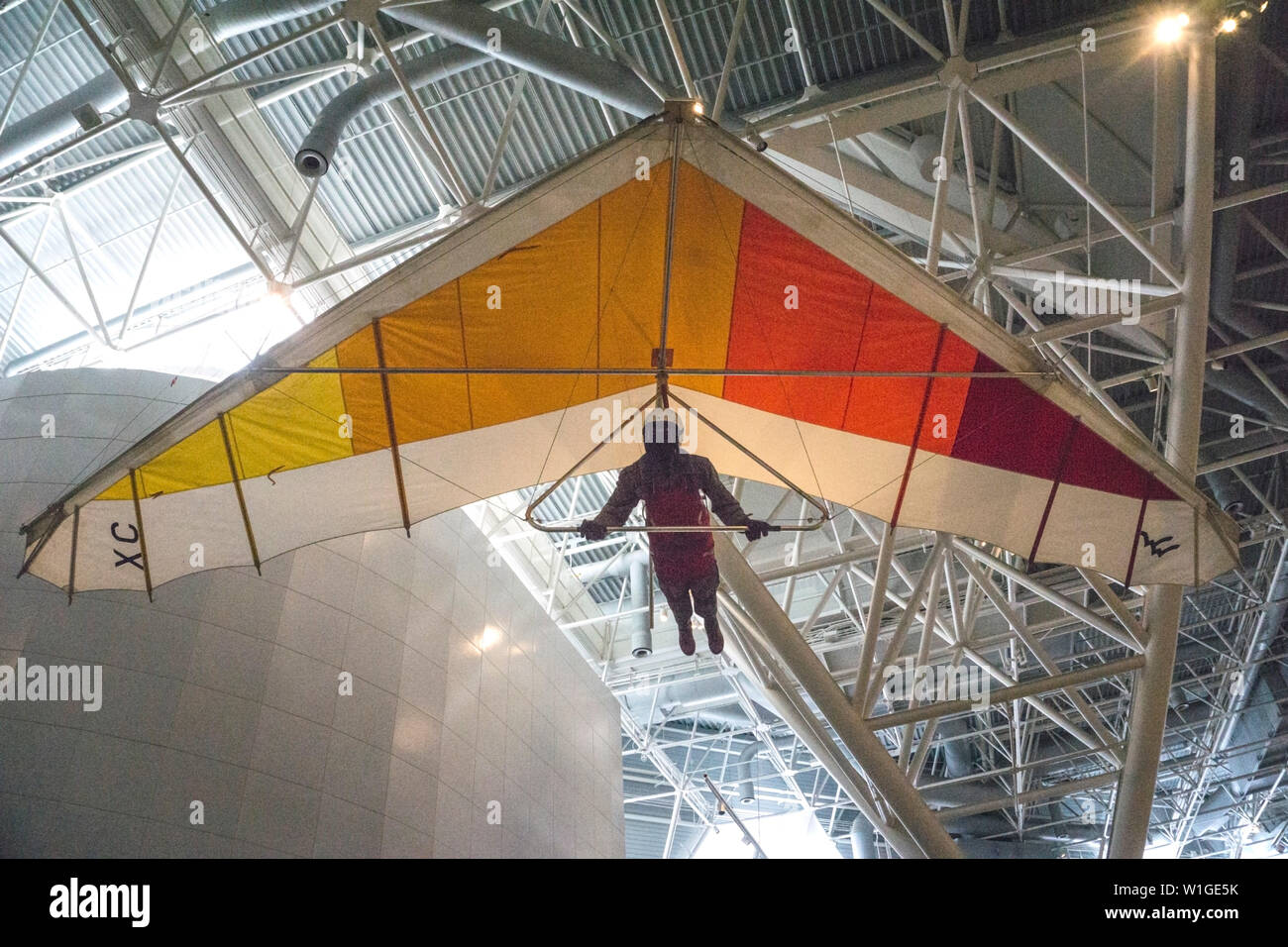 21st century delta wing hang glider is suspended from roof of lofty Canada Aviation & Space Museum in Ottawa carrying mannequin grasping steering bar Stock Photo