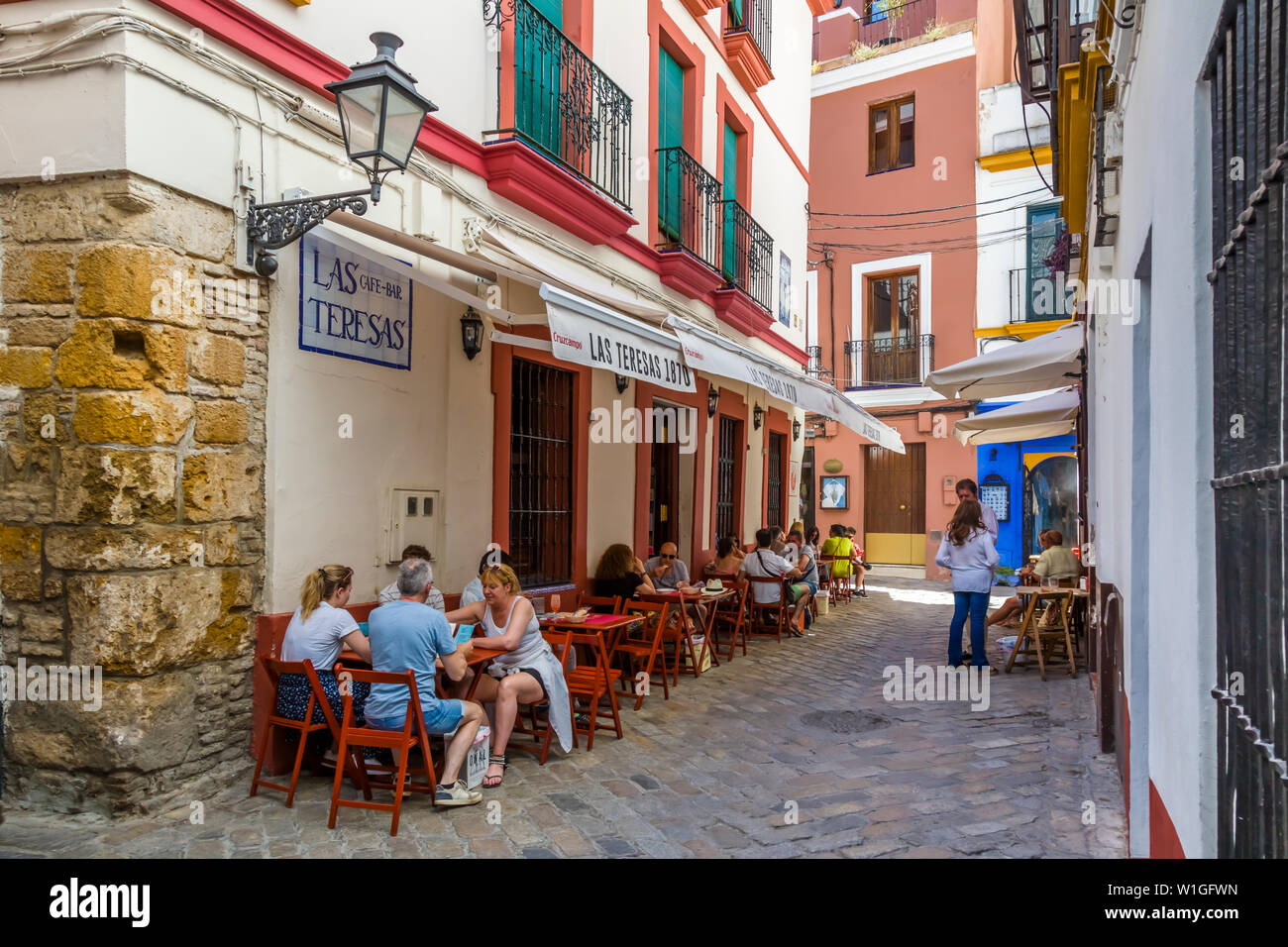 People at outdoor cafe in theBarrio de Santa Cruz or old Jewish Quarter of Seville Spain Stock Photo