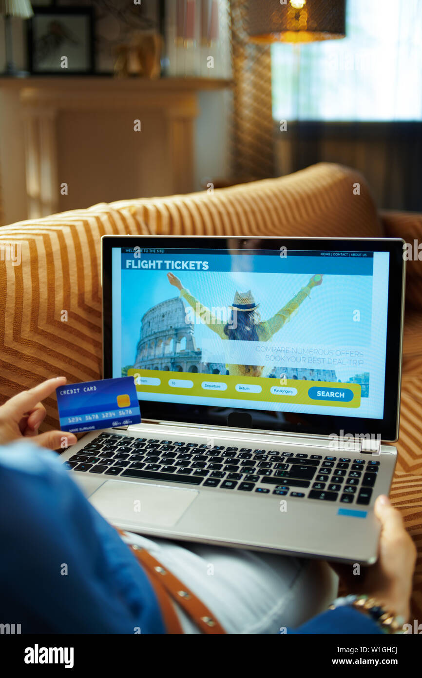 Modern Housewife With Credit Card Using Online Travel Hotel Booking Website On A Laptop While Sitting On Sofa In The Modern Living Room In Sunny Hot S Stock Photo Alamy