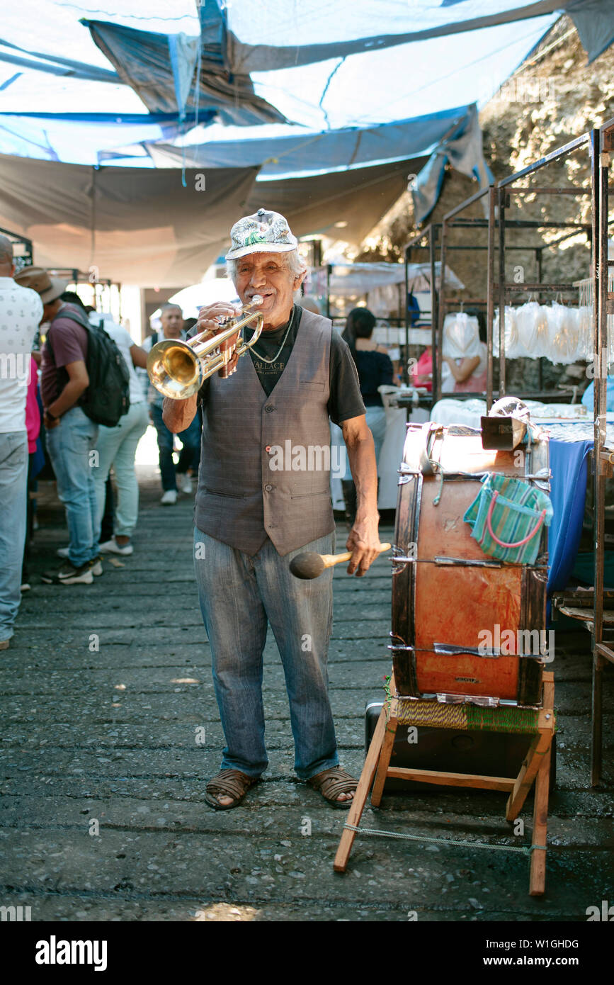 Elderly latino man singing and playing music with his trumpet and drum at Saturday's silver market. Taxco de Alarcón, Mexico. Jun 2019 Stock Photo