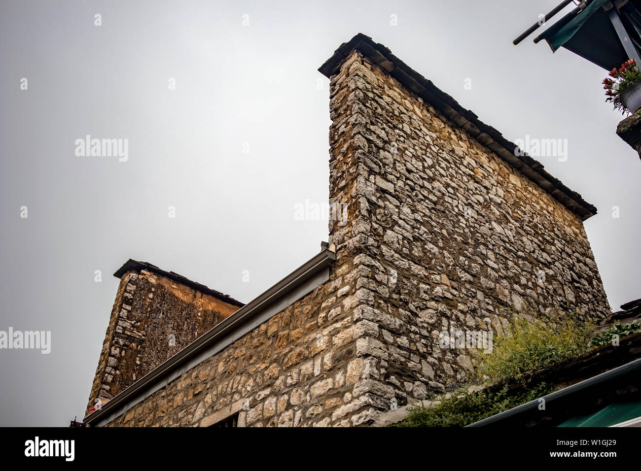 Strange roof with two side stone walls of old Greek residential building, Ioannina downtown, Greece. Moody foggy spring morning, no people Stock Photo