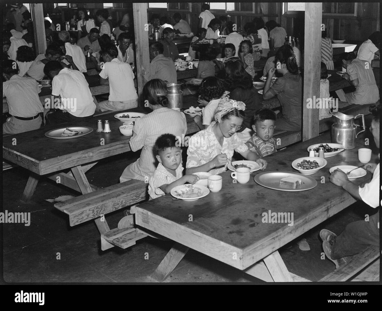 Manzanar Relocation Center, Manzanar, California. Mealtime in one of the messhalls at this War Relo . . .; Scope and content:  The full caption for this photograph reads: Manzanar Relocation Center, Manzanar, California. Mealtime in one of the messhalls at this War Relocation Authority center for evacuees of Japanese ancestry. Stock Photo