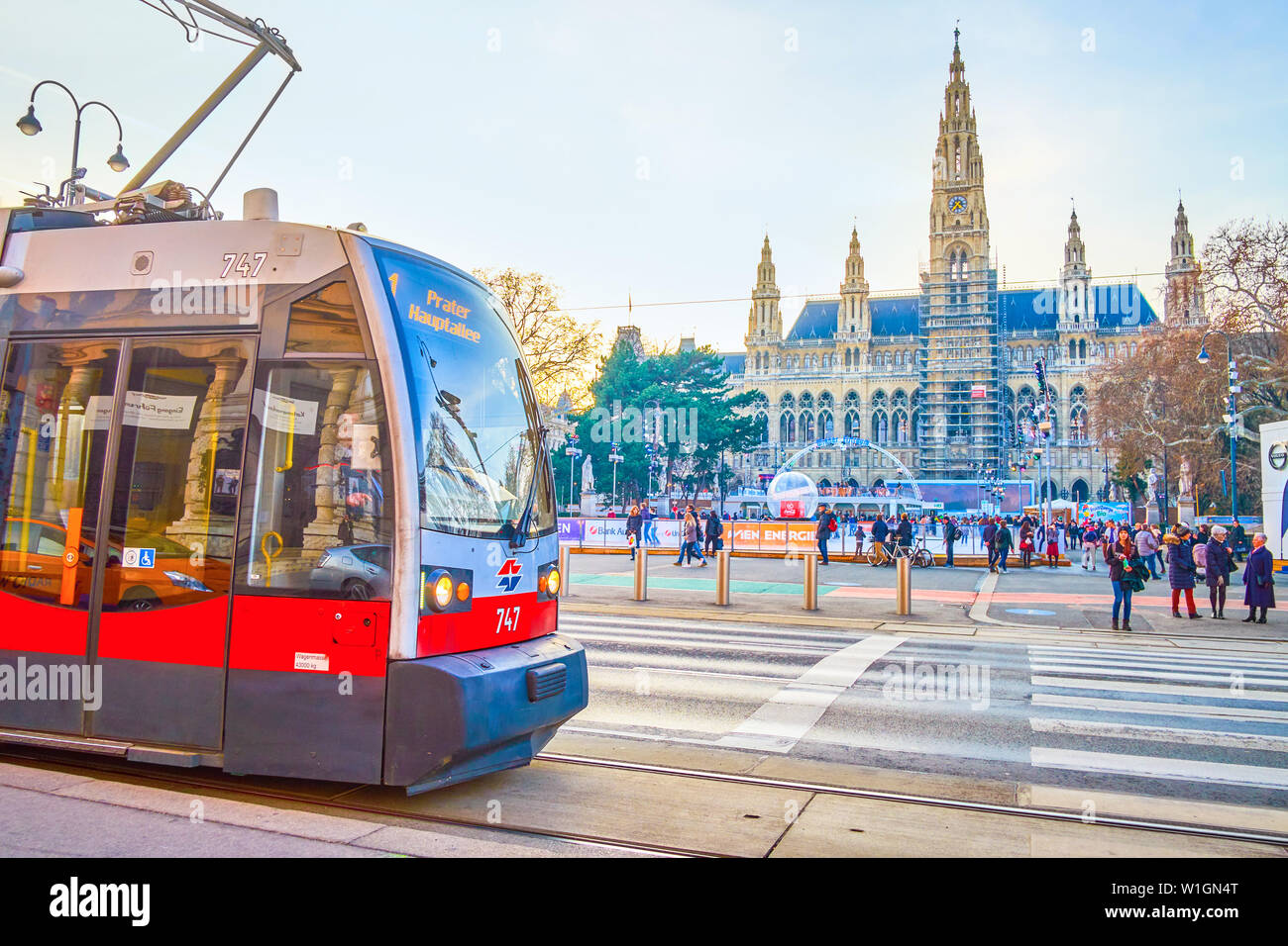 VIENNA, AUSTRIA - FEBRUARY 18, 2019: The modern tram rides along Ringstrasse, passing Rathausplatz with winter skating ring and beautiful Town Hall, o Stock Photo