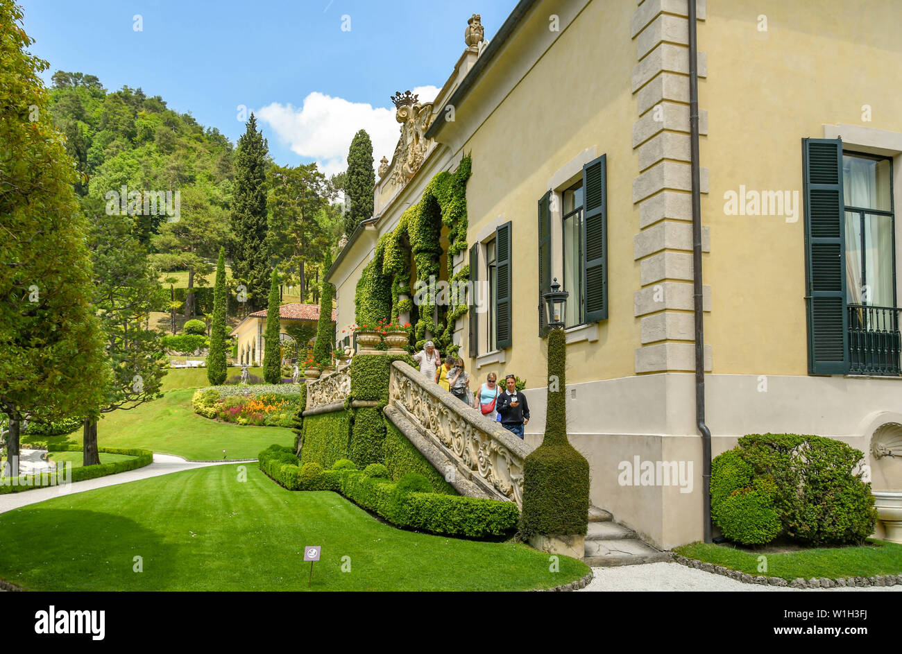 LENNO, LAKE COMO, ITALY - JUNE 2019: People in a guided tour party walking down steps from the lodge in the grounds of the Villa Balbianello in Lenno Stock Photo