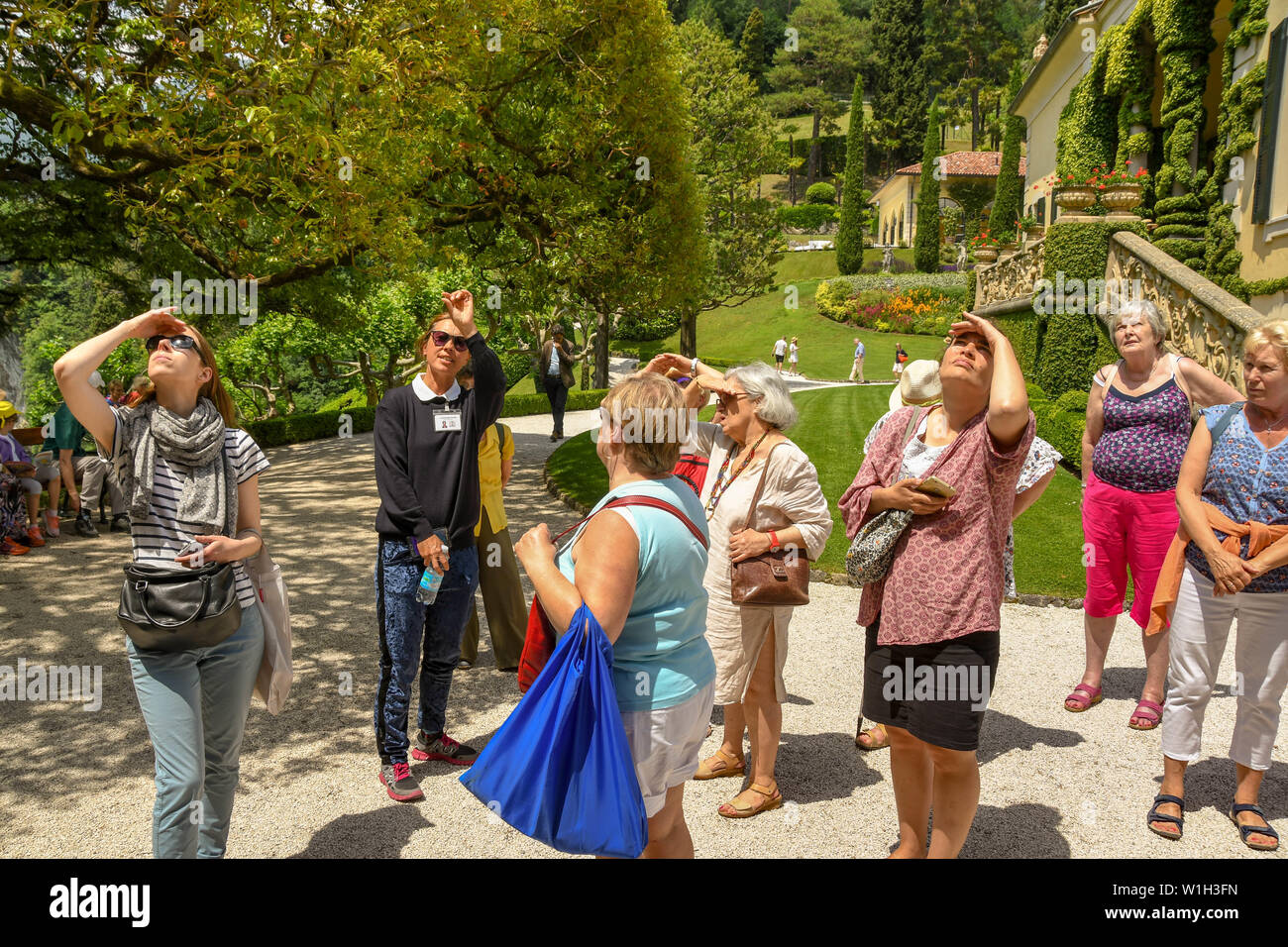 LENNO, LAKE COMO, ITALY - JUNE 2019: People in a guided tour party looking at one of the buildings in the grounds of the Villa Balbianello in Lenno on Stock Photo
