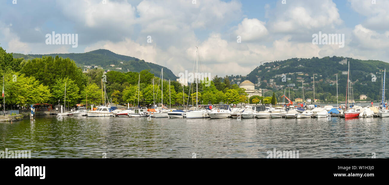 COMO, ITALY - JUNE 2019: Panoramic view of sailing boats and motor boats in harbour of Como on Lake Como. Stock Photo