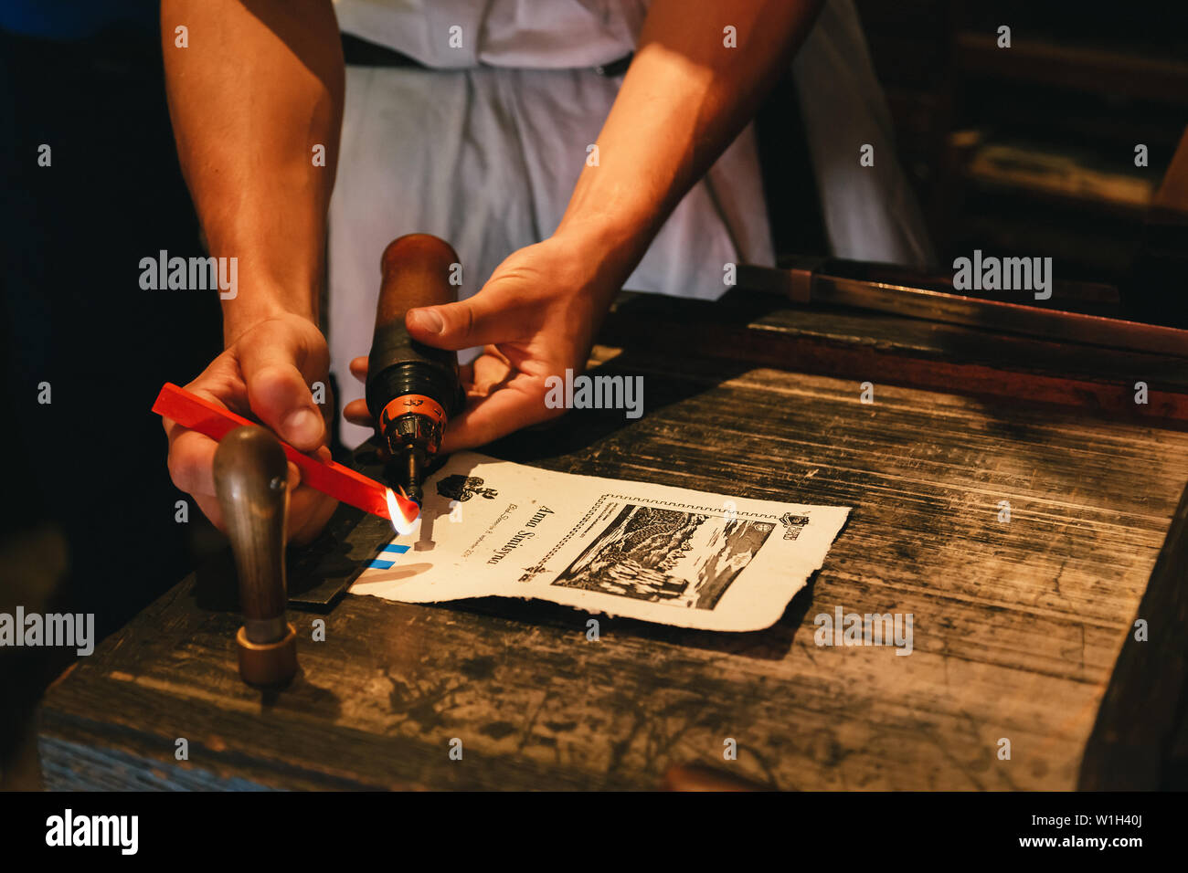 Bled, Slovenia - September, 8 2018: Close up of man's hands making a souvenir by himself, melting a red sealing wax candle with a burner to make a per Stock Photo