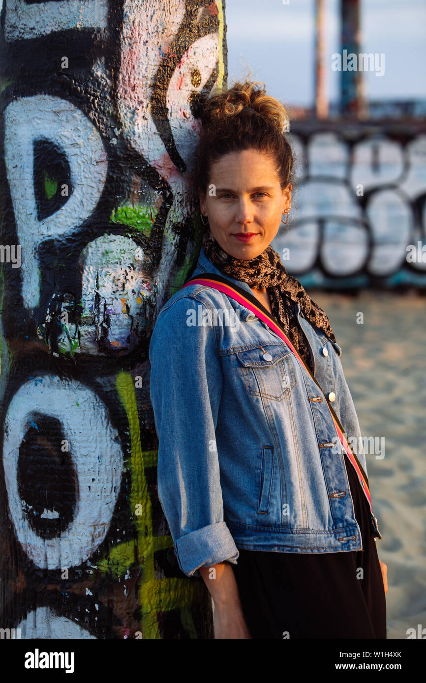 Middle age woman leaned on a graffiti palm tree in Venice Beach, Los Angeles, California, USA Stock Photo