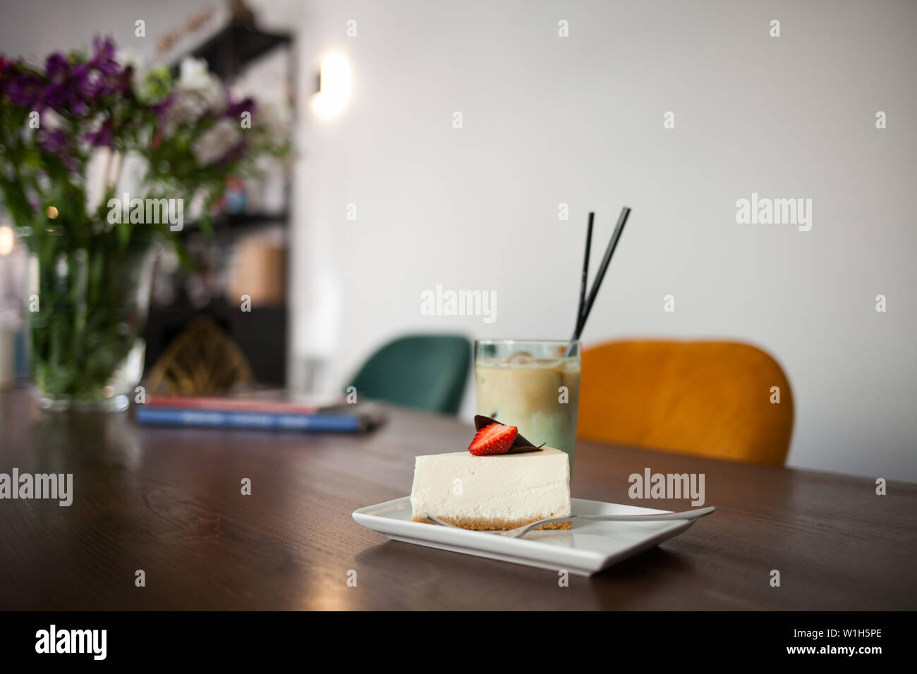 Tasty delicious cake with strawberry and Cold Coffee Frappe with ice. Cafe interior on the background. Stock Photo