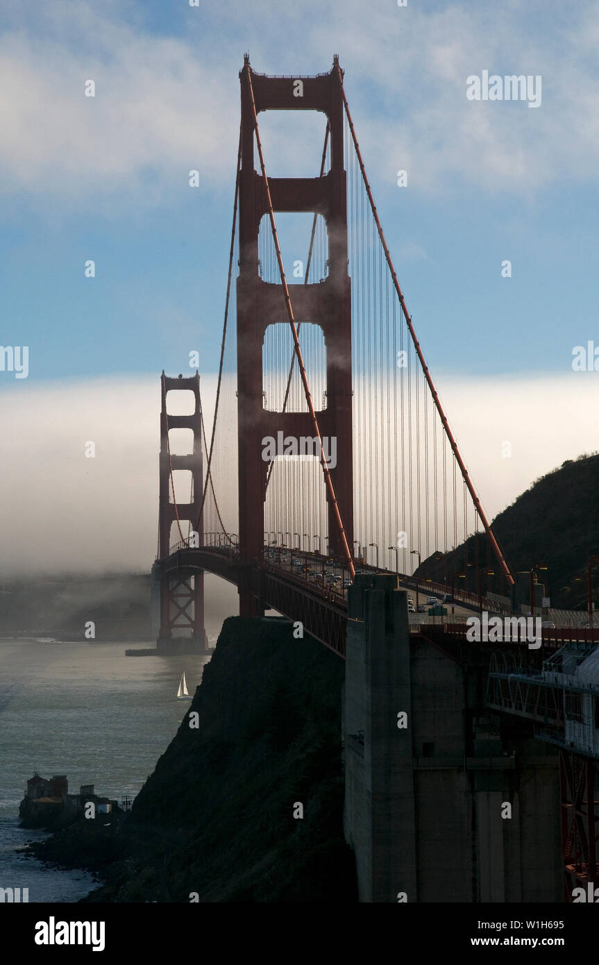 Waves of clouds weave through the Golden Gate Bridge in San Francisco Bay as a sailboat passes beneath. (c) 2009 Tom Kelly Stock Photo