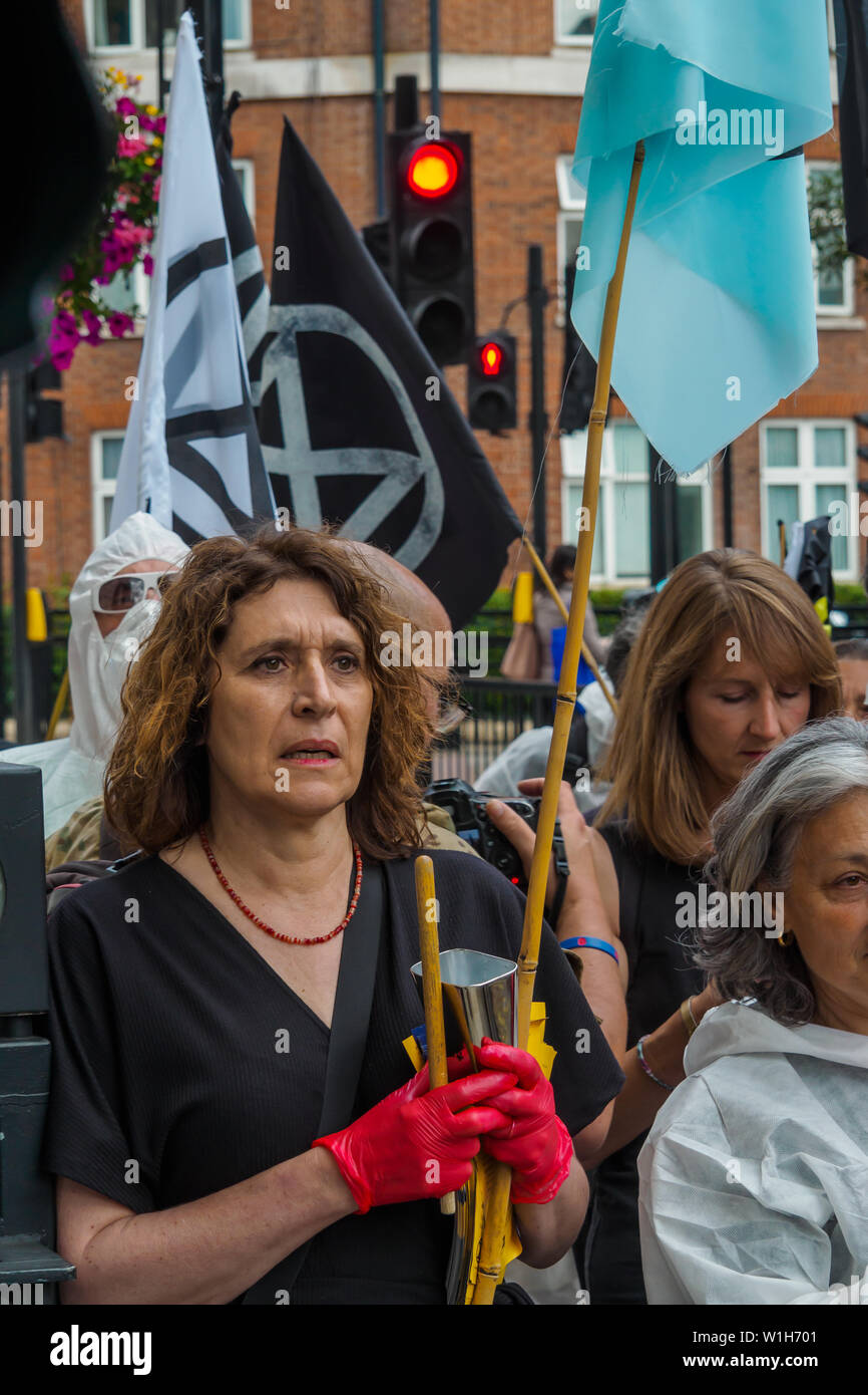 London, UK. 2nd July 2019.  Extinction Rebellion procession members listen as Carmen performs outside the offices of Petroleum Company ENI , one of the oil companies in the Oil and Gas Climate Initiative (OGCI) urging them to abandon the pretence they can combat global warming without a huge cut in oil production. The protest on the day that BP were sponsoring a Royal Opera House performance of Carmen to be relayed to 13 BP big screens starred Carmen speaking, a fine opera singer and XR drummers and a team marking the companies as crime scenes. Peter Marshall/Alamy Live News Stock Photo