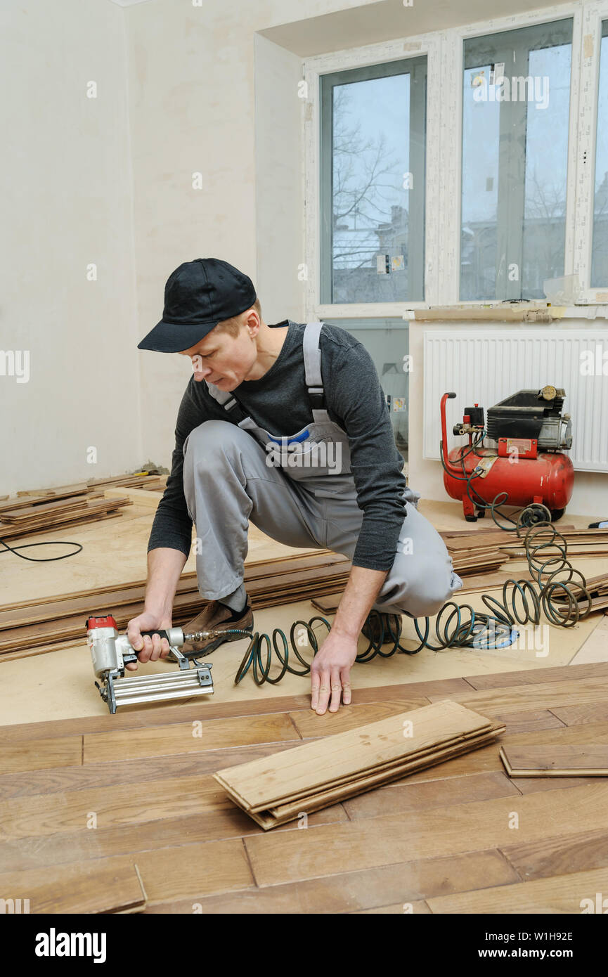 Installing A Wooden Floor The Worker Fixes The Board Using