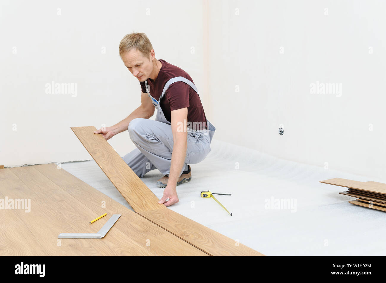 Installation of a laminate floorboard. The worker is attaching one bar