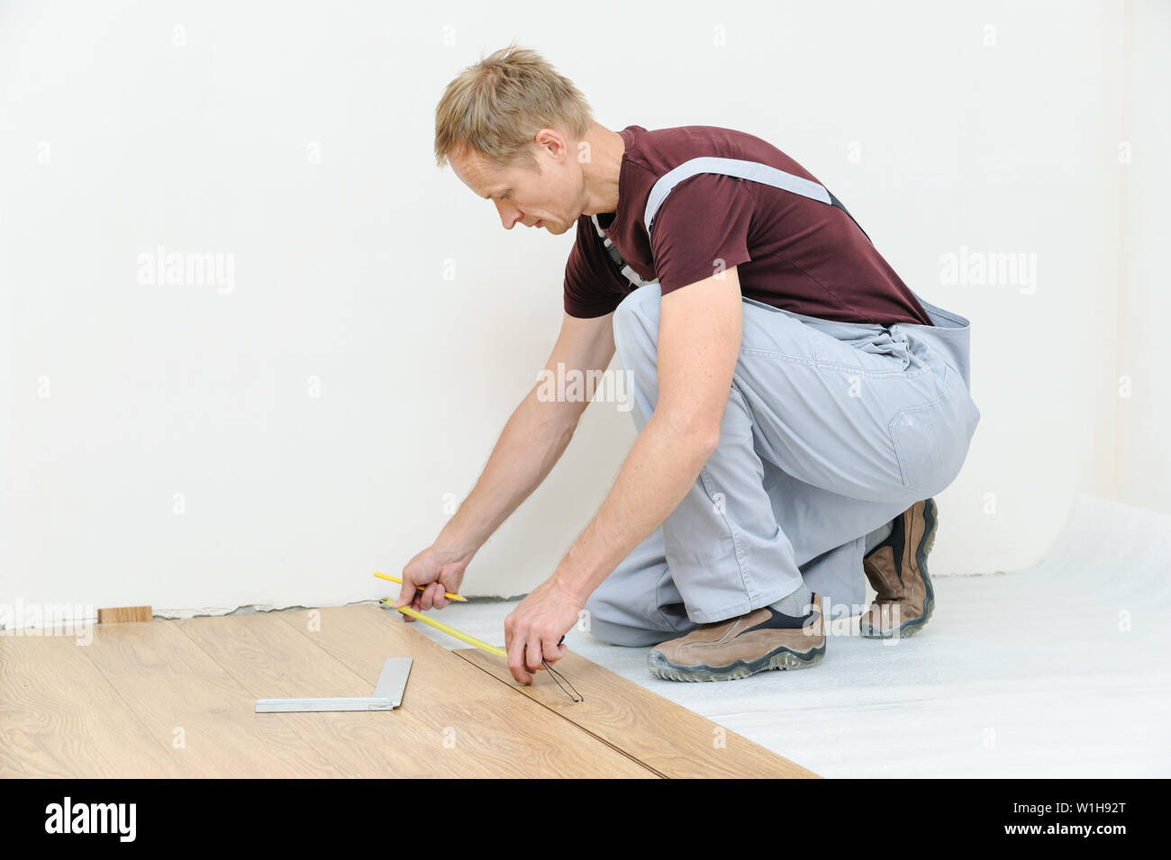 Installation of a laminate floorboard. The worker is measuring the