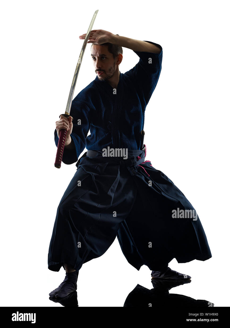 one caucasian man practicing  laido  Katori Shinto ryu isolated shadow silhouette white background Stock Photo