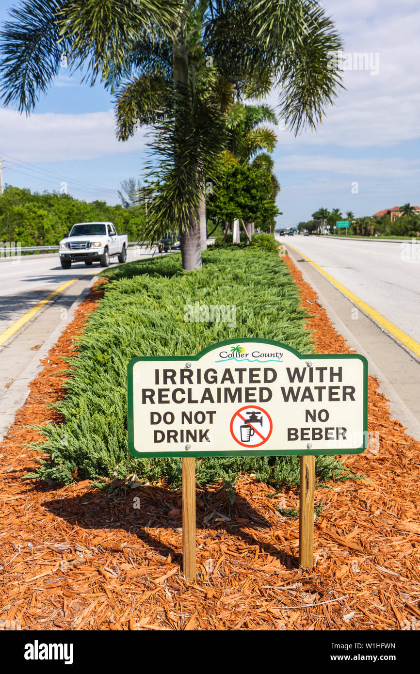 Naples Florida,US highway Route 41,Tamiami Trail,road,pickup truck,median,landscaping,sign,irrigated with reclaimed water,bilingual sign,Spanish,Engli Stock Photo