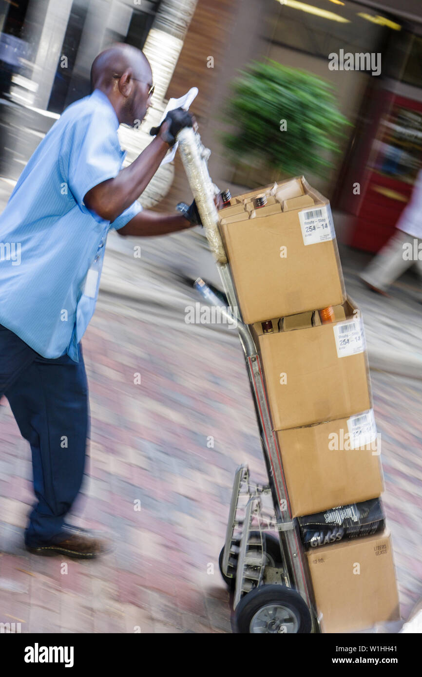 Orlando Florida,downtown,Black Blacks African Africans ethnic minority,adult adults man men male,worker,workers,laborer,push,hand truck cart,dolly,car Stock Photo