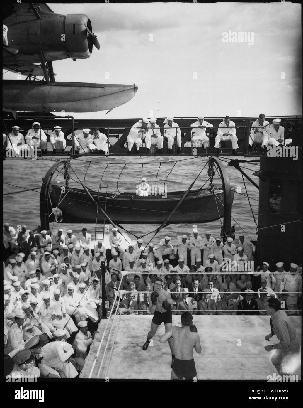 President Truman and party aboard USS AUGUSTA for return trip from the Potsdam Conference. Watching boxing bouts during smoker on well deck.; General notes:  Use War and Conflict Number 887 when ordering a reproduction or requesting information about this image. Stock Photo