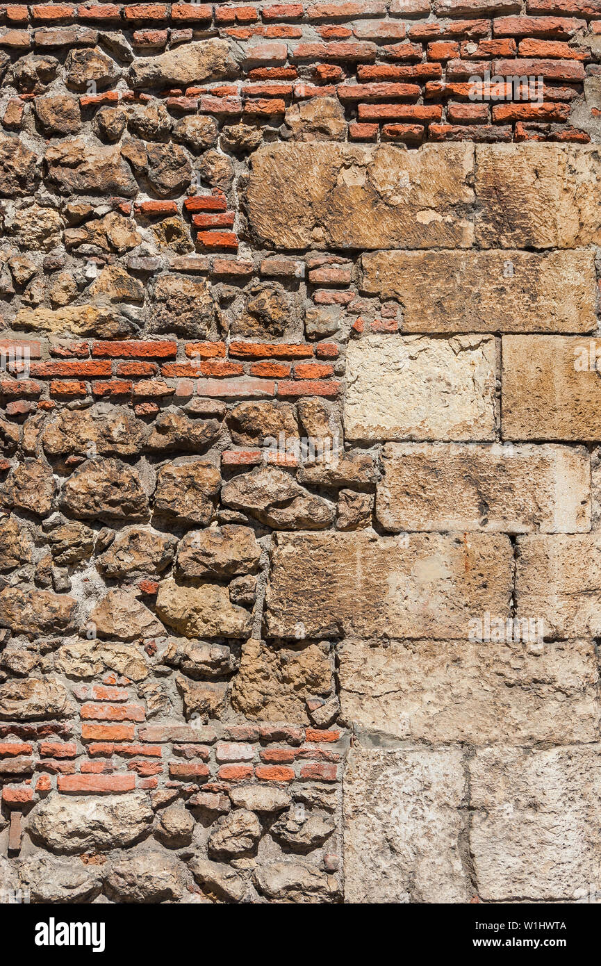 Composite old stone and bricks wall with rough surface as background Stock Photo