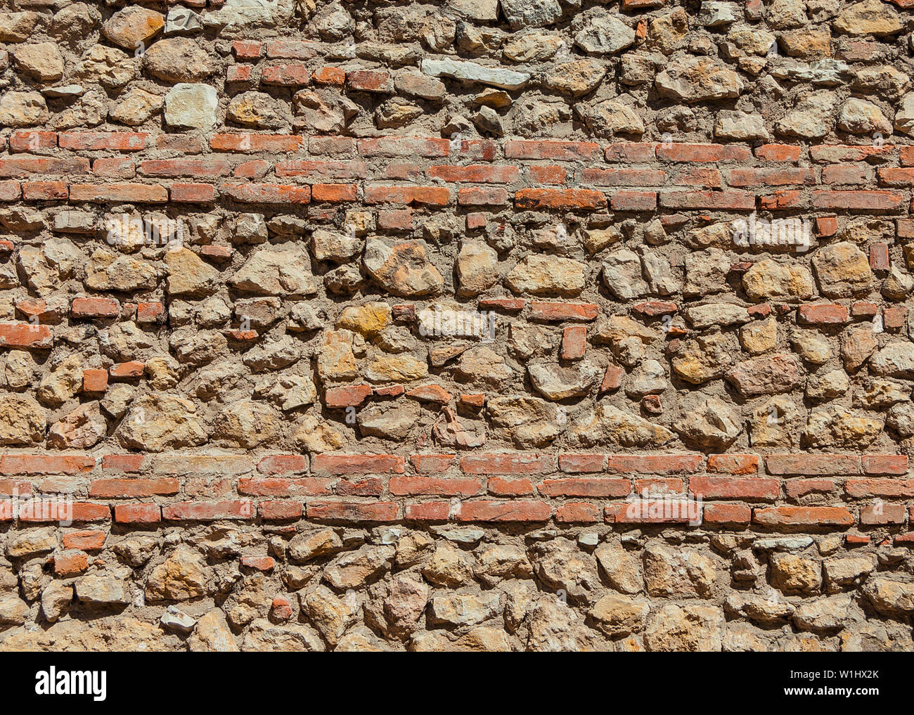 Composite old stone and bricks wall with rough surface as background Stock Photo