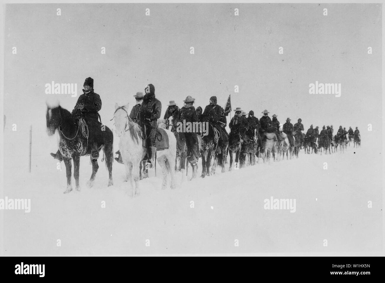 Return of Casey's scouts from the fight at Wounded Knee, 1890--91. Soldiers on horseback plod through the snow Stock Photo