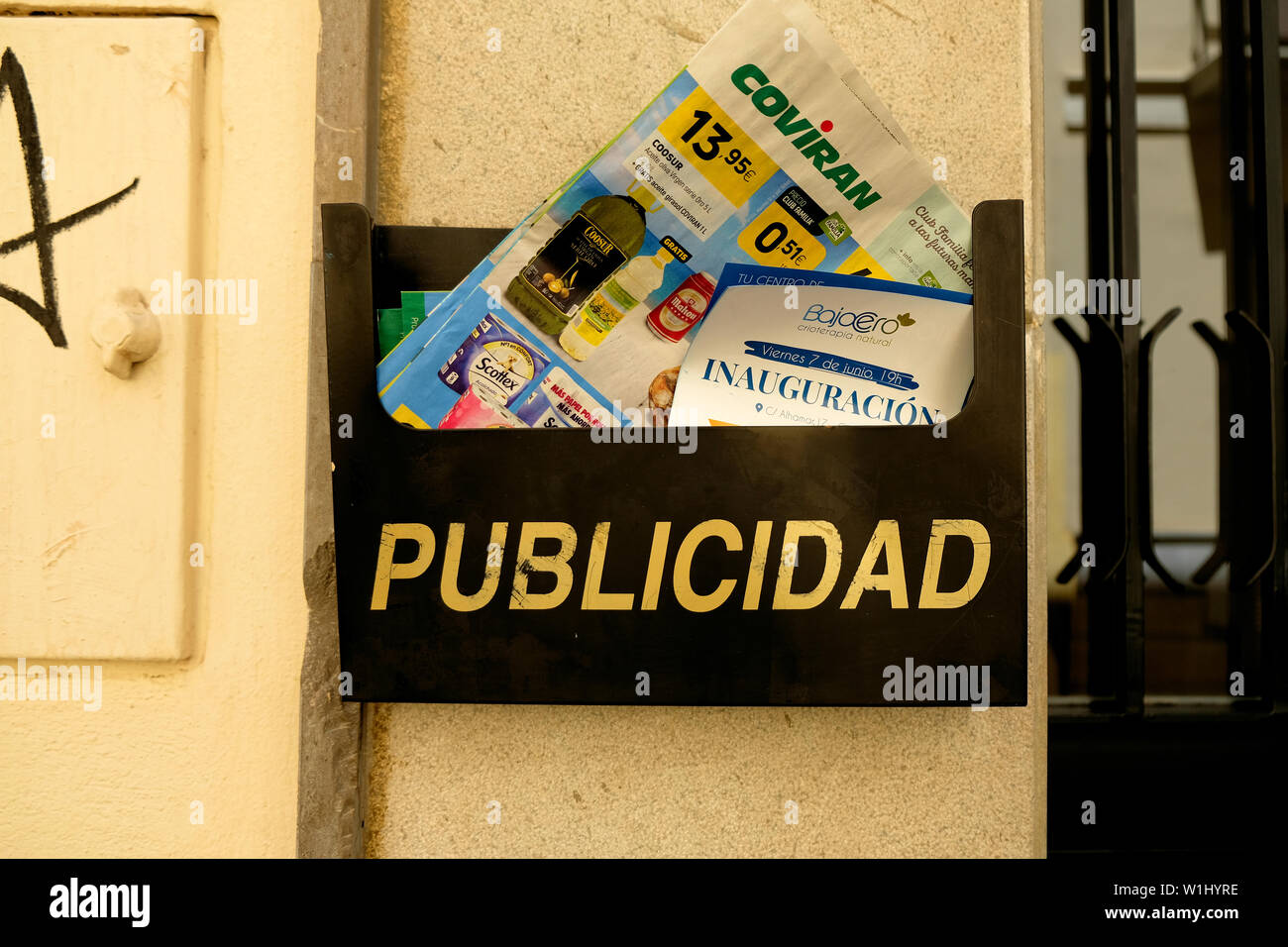 Publicidad mailbox with delivered publicity flyers and circulars on a wall outside an apartment in Granada, Spain; publicity in Spanish. Stock Photo