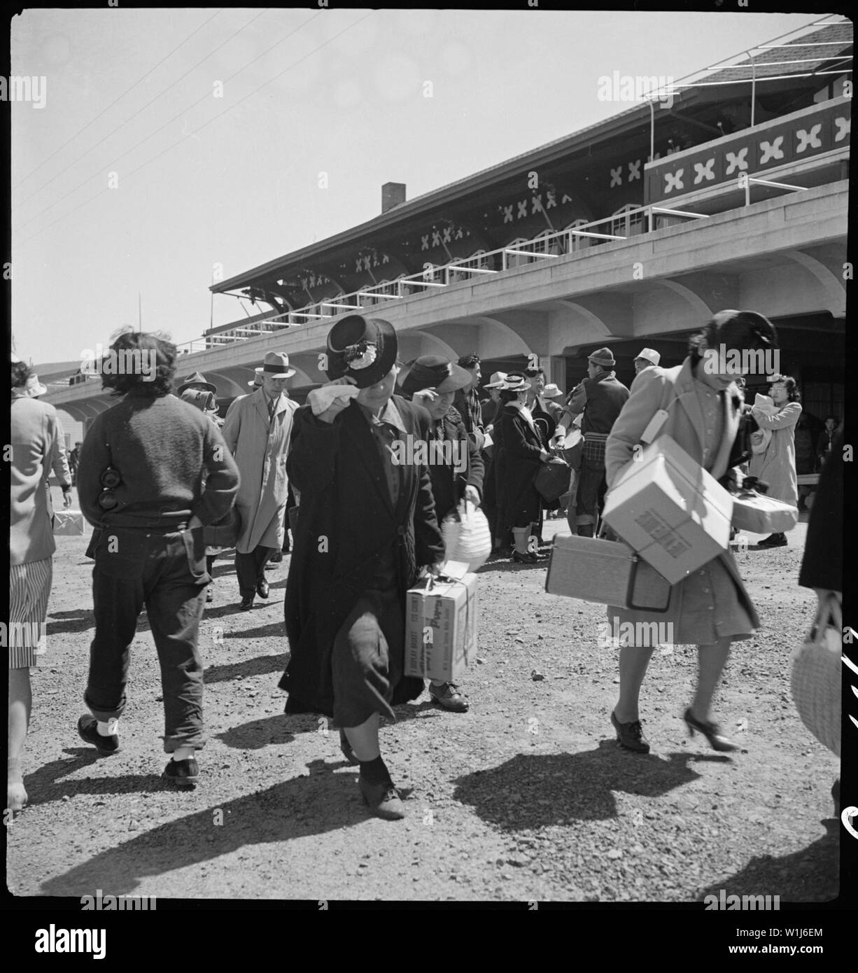 San Bruno, California. Families of Japanese ancestry arrive at assembly center at Tanforan Race Tra . . .; Scope and content:  The full caption for this photograph reads: San Bruno, California. Families of Japanese ancestry arrive at assembly center at Tanforan Race Track. Evacuees will be transferred later to War Relocation Authority centers where they will be housed for the duration. Stock Photo