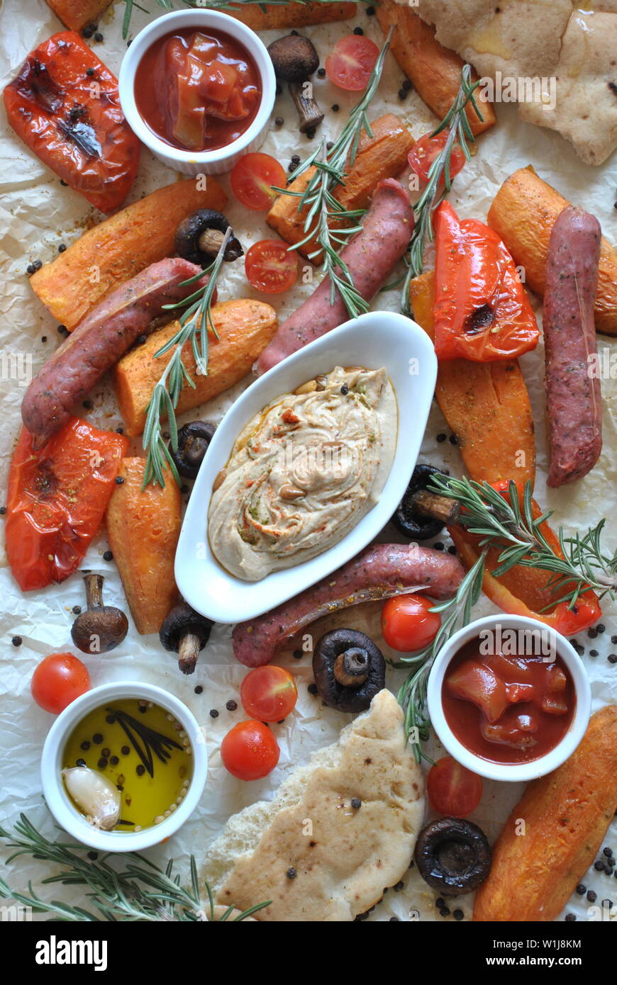 Grilled sausages and vegetables platter served with humus and pita