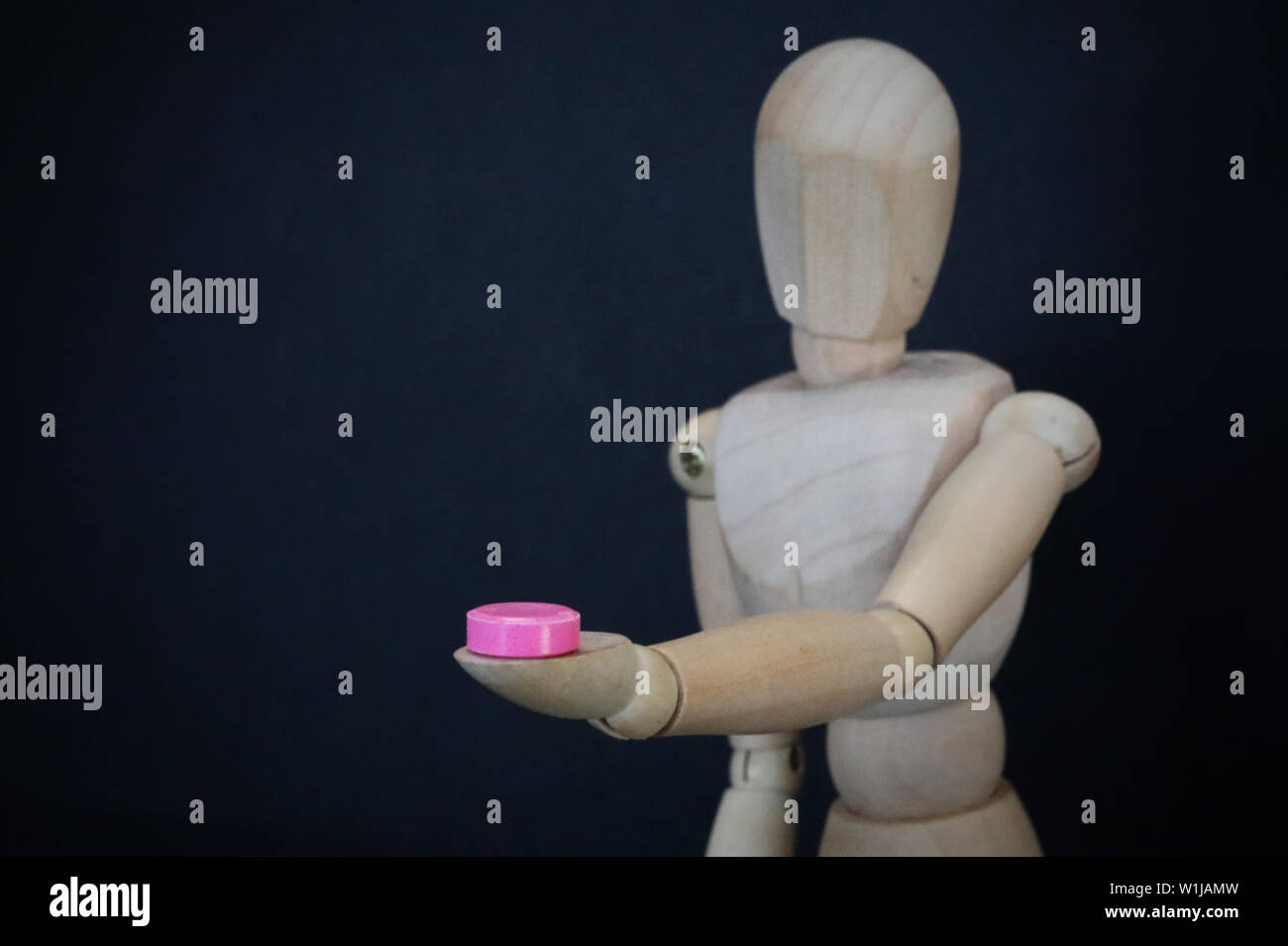 sinlgle close up figure holding a small pink pill. cold and flue or party drug recreational illicit drug testing concept. Personal choice strength cha Stock Photo