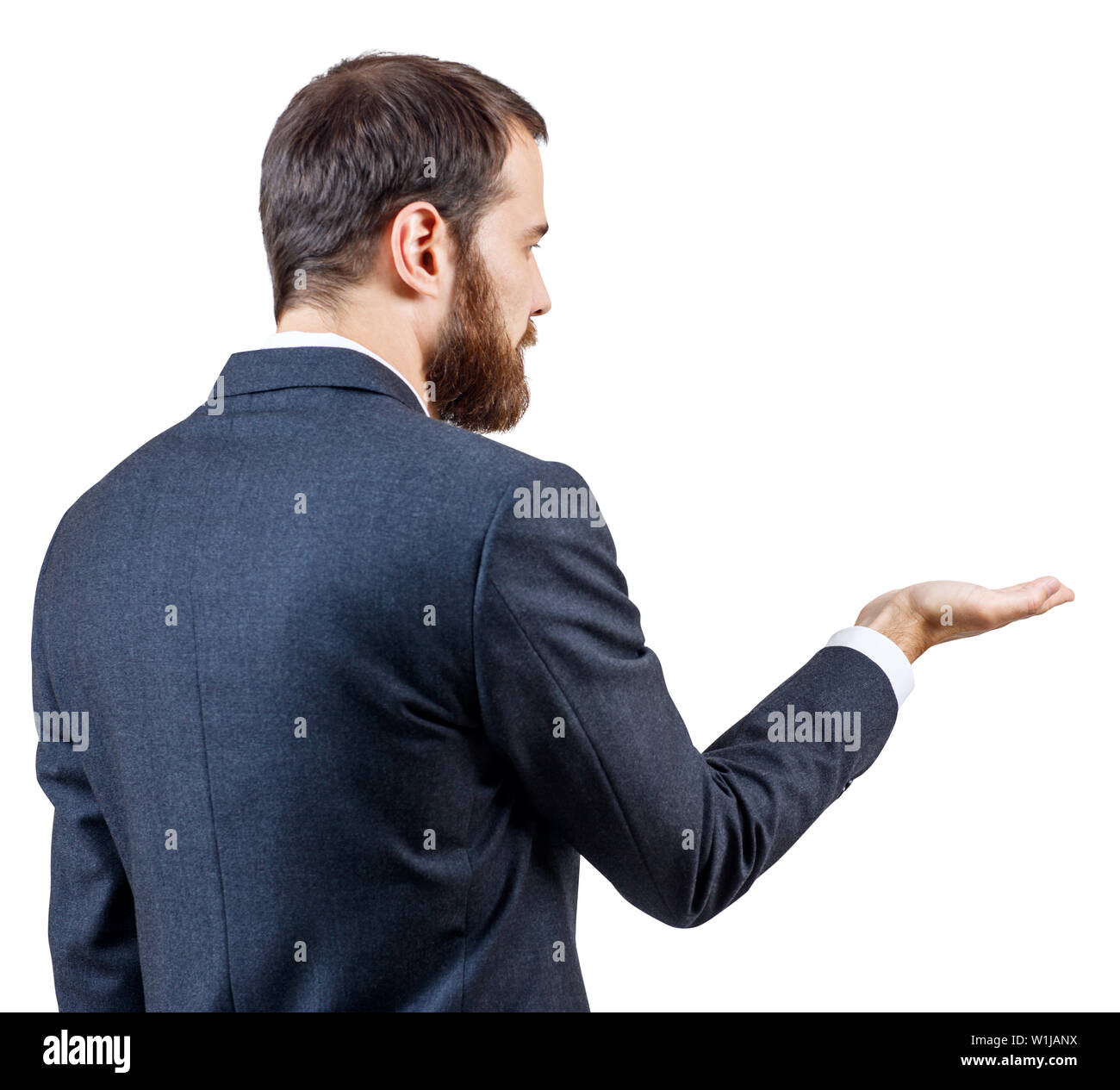 Rear view on man in business suit standing and shows outstretched hand with open palm. Stock Photo