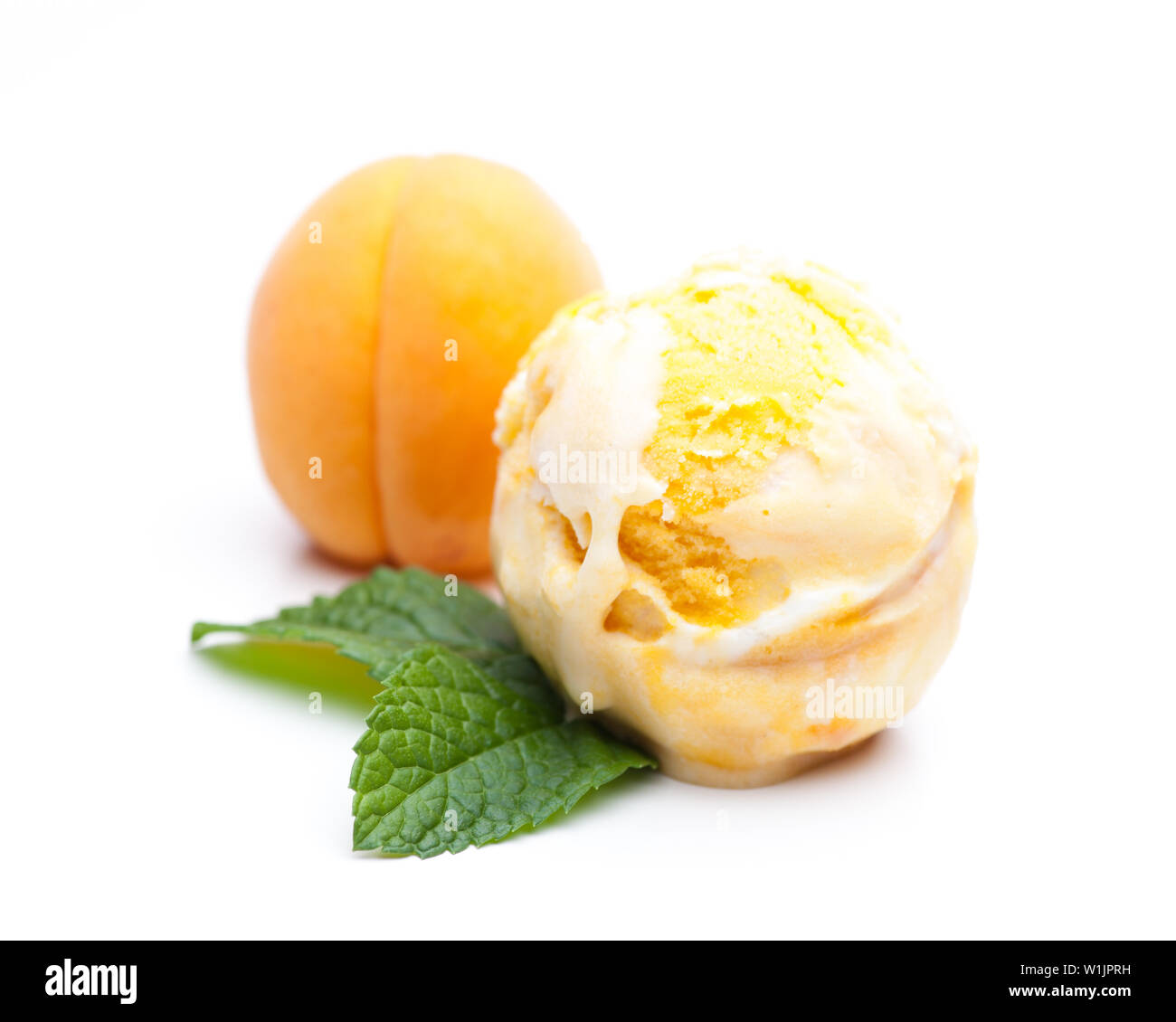 A scoop of apricot ice cream with mint and a real apricot isolated on white background Stock Photo
