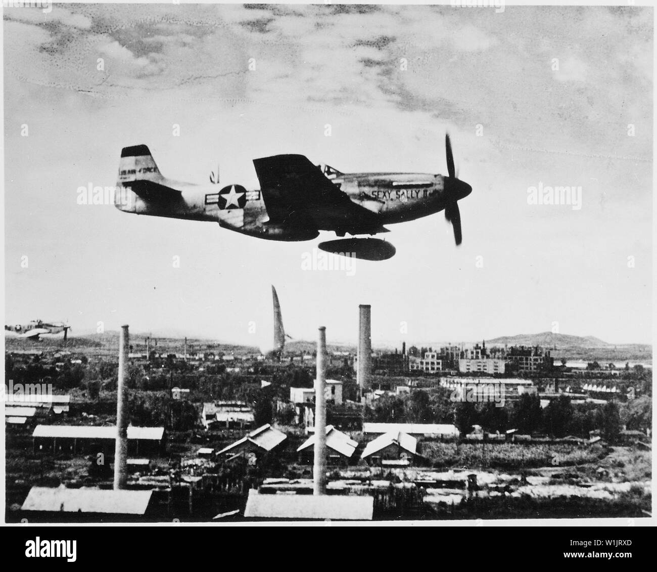 A Mustang fighter aircraft releases two external fuel tanks. One is