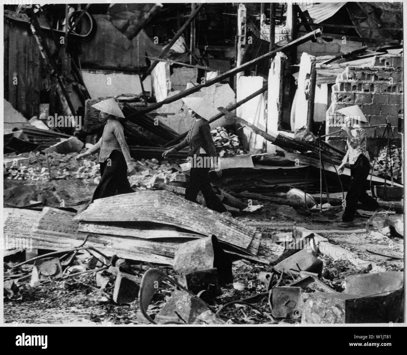 Three Vietnamese women move back into the Cholon area after Viet Cong attack that left a two-block area leveled, in hopes of salvaging meager belongings. Saigon, January 31, 1968., 1958 - 1974; General notes:  Use War and Conflict Number 421 when ordering a reproduction or requesting information about this image. Stock Photo